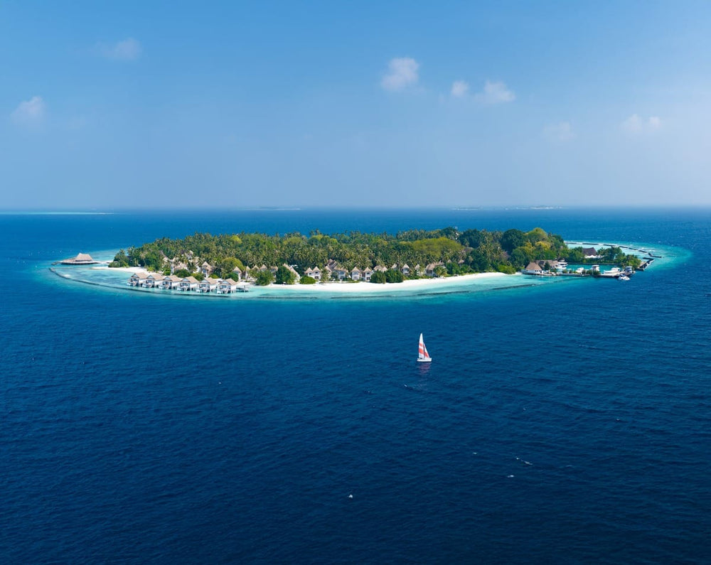 Bandos seen from the air, the wooded island ringed by the house reef you can swim right around