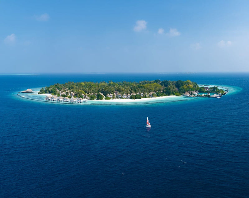 Bandos Maldives seen from out at sea, with its beach and water villas.