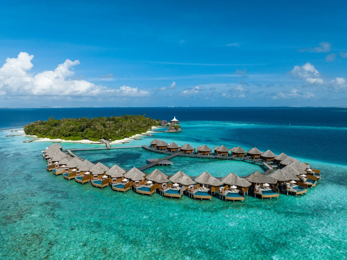 Baros Maldives from the air, the overwater villas curving out from the island into the lagoon