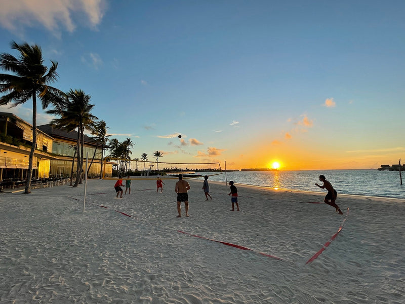 A beach volleyball game at sunset at Hard Rock Hotel Maldives.
