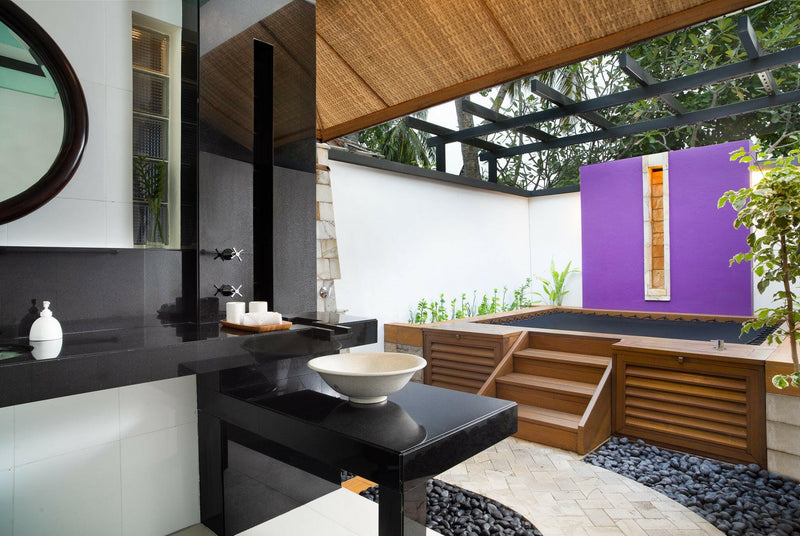 A Beachfront Rainmist Villa bathroom at Dhawa Ihuru, black vanity beside a planted purple courtyard.