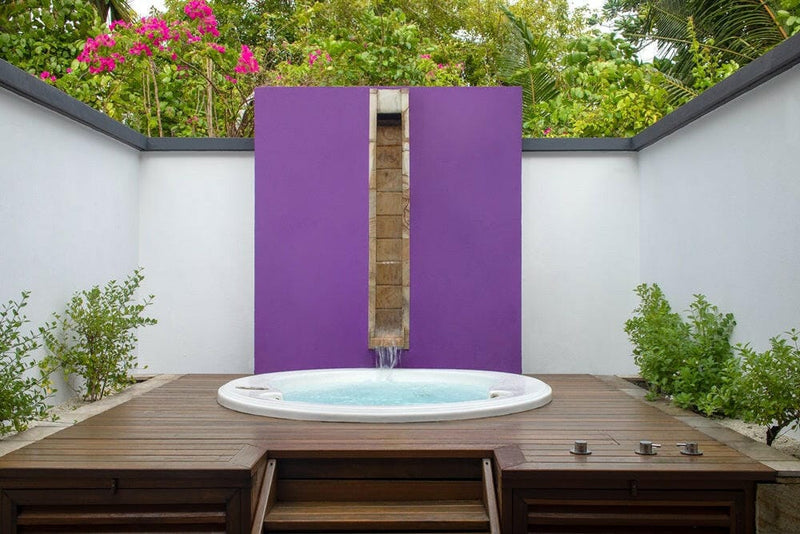 A jet pool at Dhawa Ihuru, round bubbling tub on timber decking below purple wall panels.