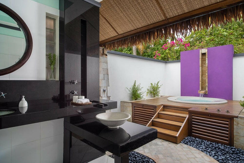 A villa bathroom at Dhawa Ihuru, bowl basin on a black vanity looking out to the round jet pool.