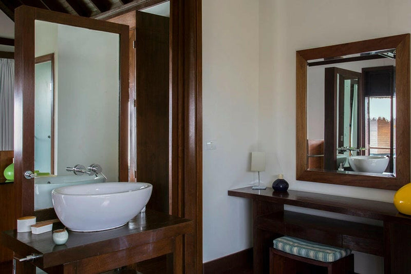 A villa washbasin and dressing table at Coco Bodu Hithi, the sea reflected in the timber-framed mirror
