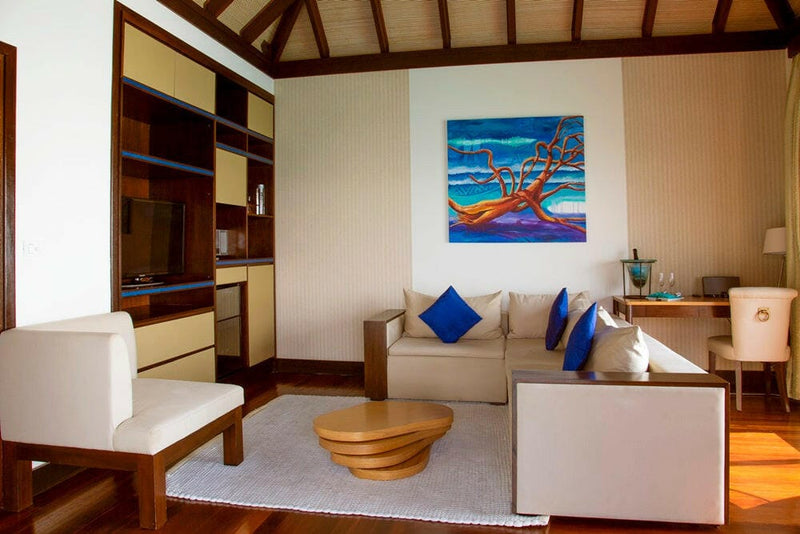 A villa living room at Coco Bodu Hithi, two white armchairs facing the sofa across a round timber table