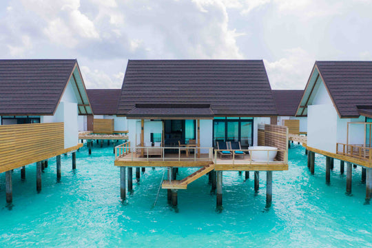 Fushifaru Maldives, Lhaviyani Atoll — sun loungers and a parasol on a water villa deck above the lagoon