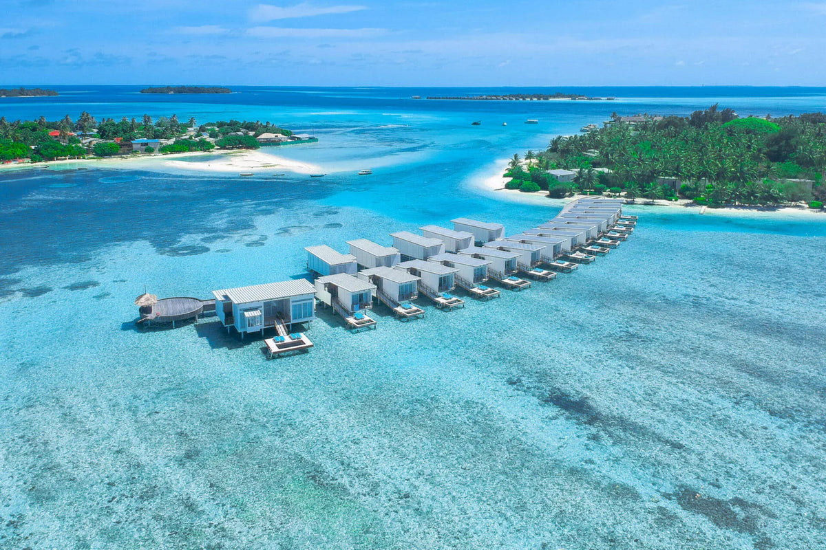 The overwater villa row at Holiday Inn Resort Kandooma Maldives from the air, over the lagoon.