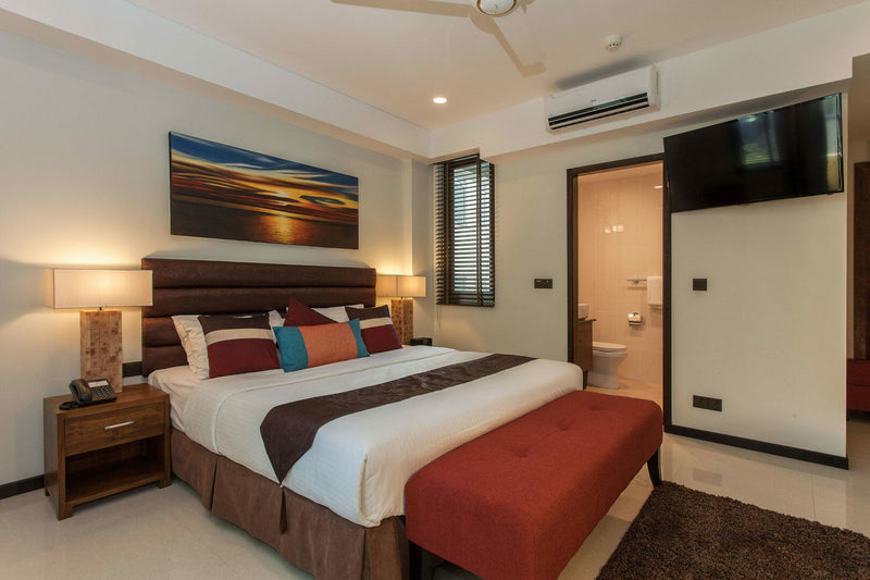 Bedroom at The Somerset Hotel with a red bed runner and wooden furniture