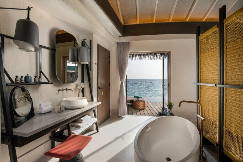 A villa bathroom at InterContinental Maamunagau, round tub and a stone counter under twin mirrors.
