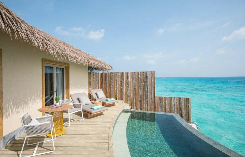 The deck of an overwater villa at InterContinental Maamunagau, loungers beside a pool over the sea.