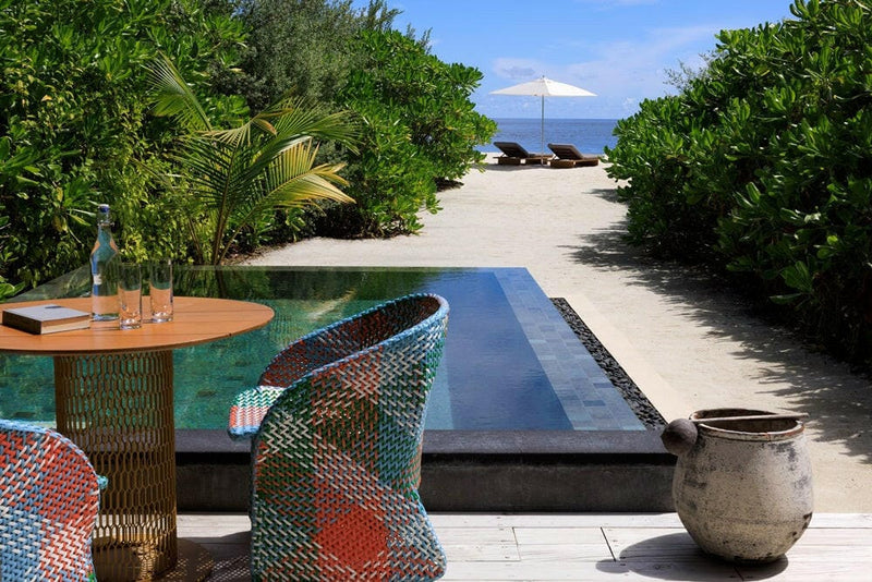 A garden pool at InterContinental Maamunagau leading to a parasol and loungers on the sand.