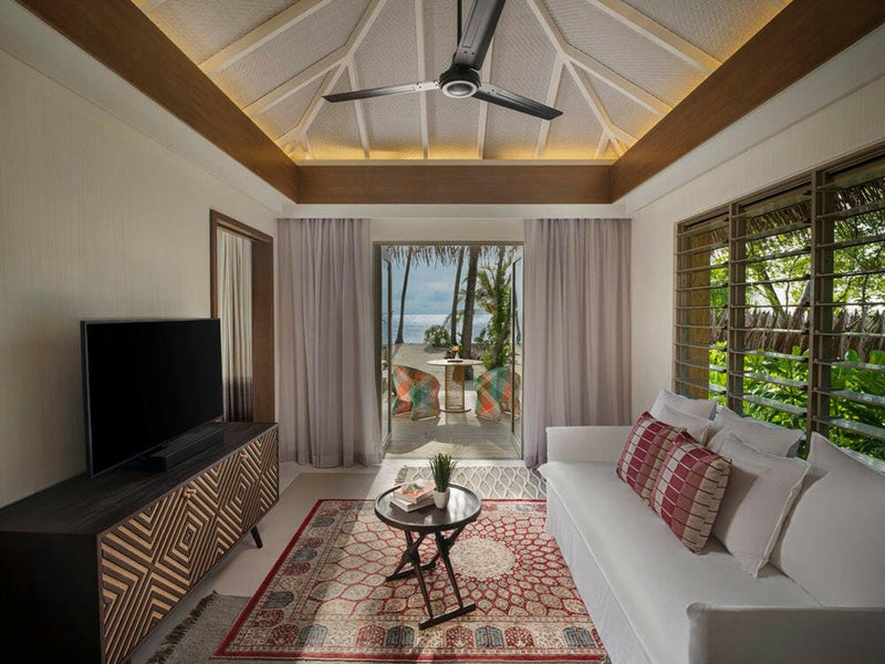 A villa living room at InterContinental Maamunagau, white sofa on a deep red patterned rug.