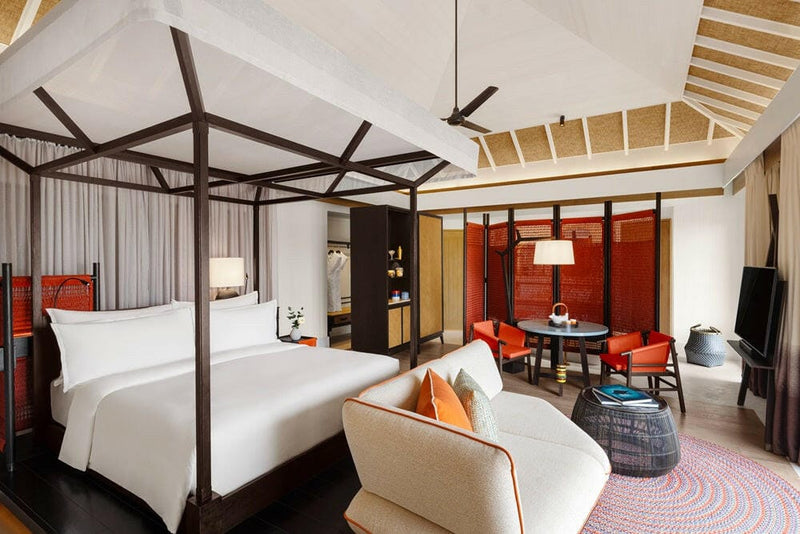 A bedroom at InterContinental Maamunagau, canopy frame over the bed and red lacquered wall panels.
