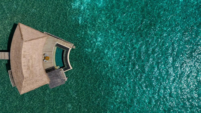Looking straight down on one overwater villa at InterContinental Maamunagau, its curved deck and pool.