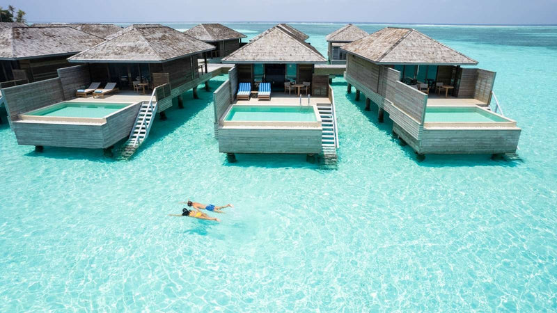 Jawakara Islands Maldives, Lhaviyani Atoll: overwater villas with a swimmer in the shallow lagoon below