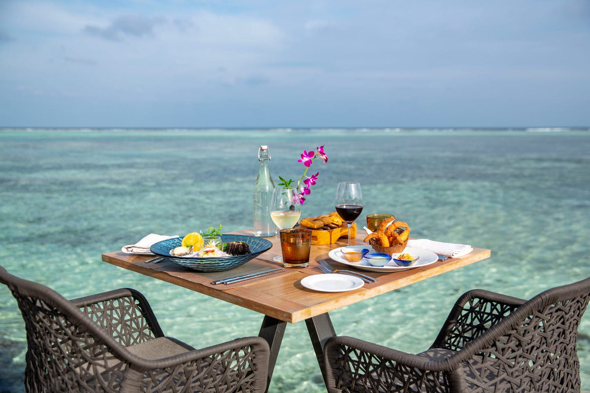 A table laid for lunch on the sand at the water's edge, Four Seasons Resort Maldives at Kuda Huraa