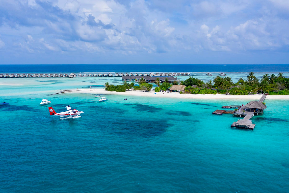 A seaplane on the water beside the arrival jetty at LUX* South Ari Atoll, the island behind