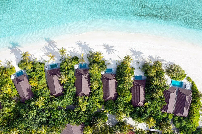 Beach villas at The Standard Huruvalhi from the air, red roofs and pools set back from a wide white beach.