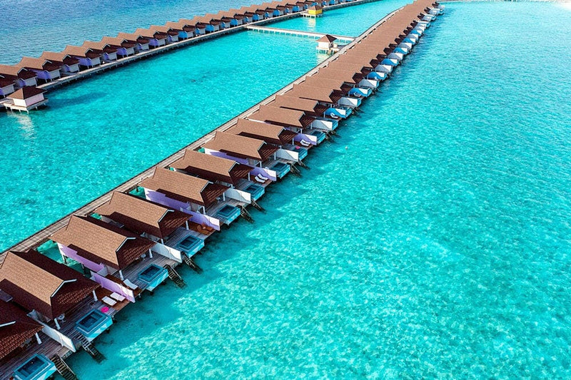 The water villa jetty at The Standard Huruvalhi from above, decks and loungers ranged along the lagoon.