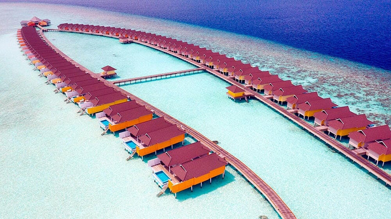Water villas at The Standard Huruvalhi from the air, orange and blue loungers along a long timber jetty.