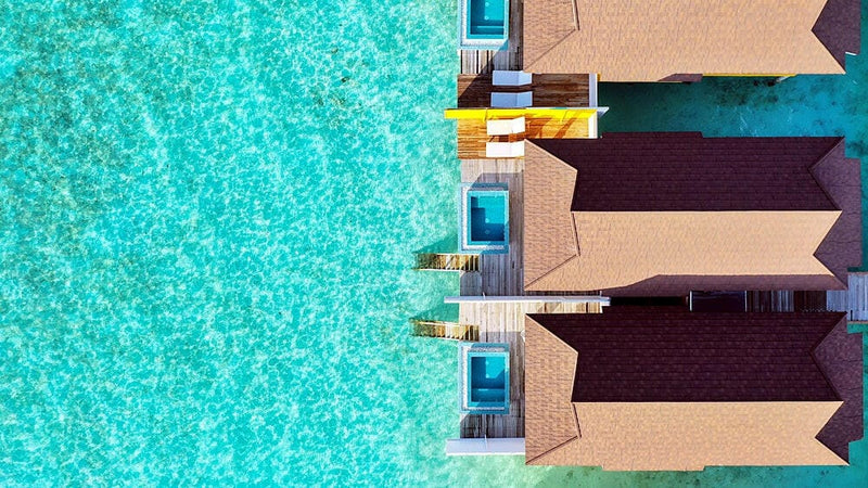 Water villas at The Standard Huruvalhi from directly above, red roofs and plunge pools over turquoise.