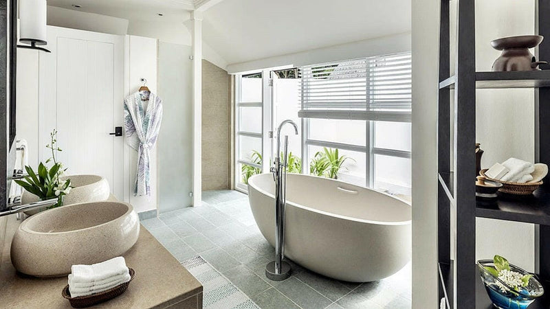 A villa bathroom at Four Seasons Kuda Huraa, a round stone basin beside a freestanding tub