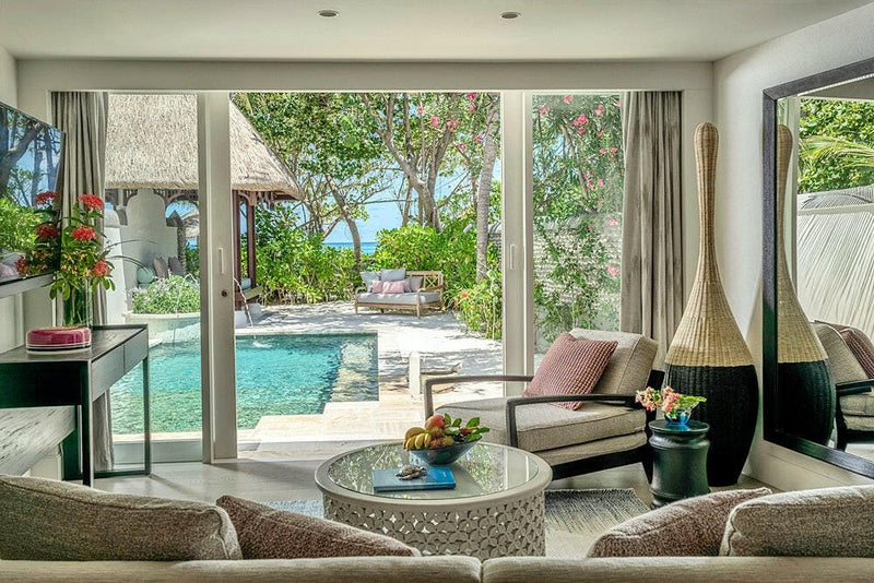 The sitting area of a villa at Four Seasons Kuda Huraa, doors folded back onto the private pool and garden