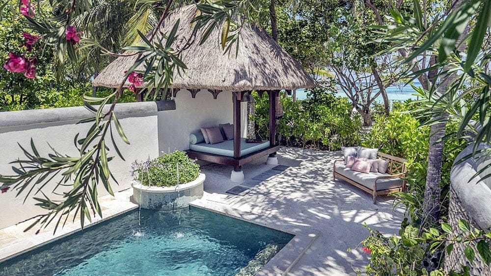 A beach villa at Four Seasons Kuda Huraa, a thatched pavilion and private pool framed by bougainvillea