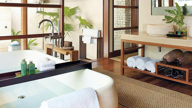 A spa treatment room at Four Seasons Kuda Huraa, twin massage beds set among potted plants