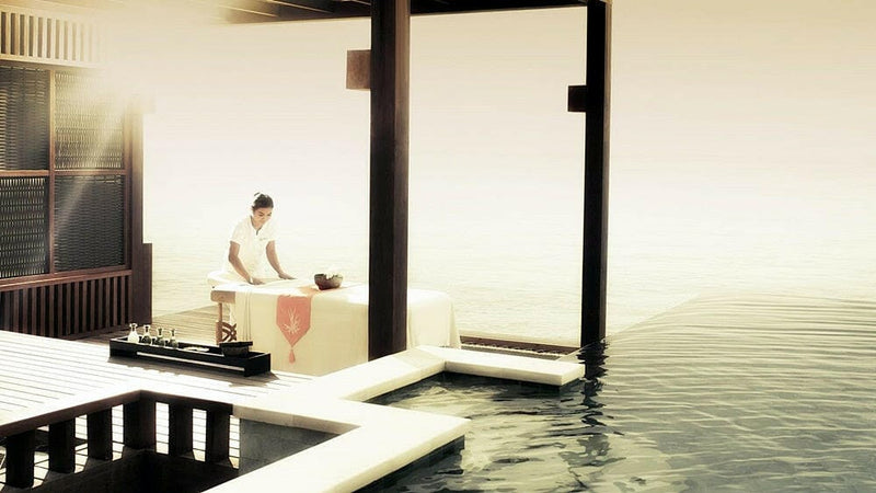 A guest sitting in an overwater pavilion at Four Seasons Kuda Huraa, the lagoon beyond