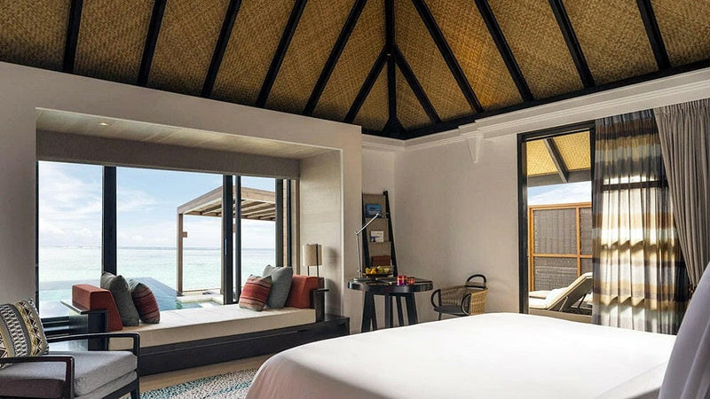 A water villa bedroom at Four Seasons Kuda Huraa, the bed facing doors open to the sea