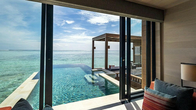 Looking out from a water villa at Four Seasons Kuda Huraa to its infinity pool and a shaded deck above the lagoon