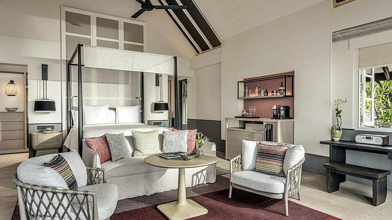 A villa bedroom at Four Seasons Landaa Giraavaru, a four poster bed with a sofa and writing desk