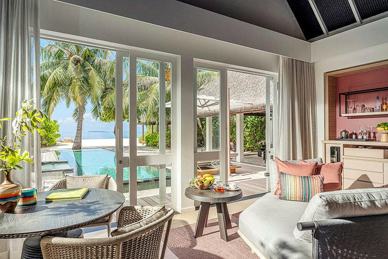 The living area of a villa at Four Seasons Landaa Giraavaru, a hanging chair beside doors open to the pool and sea