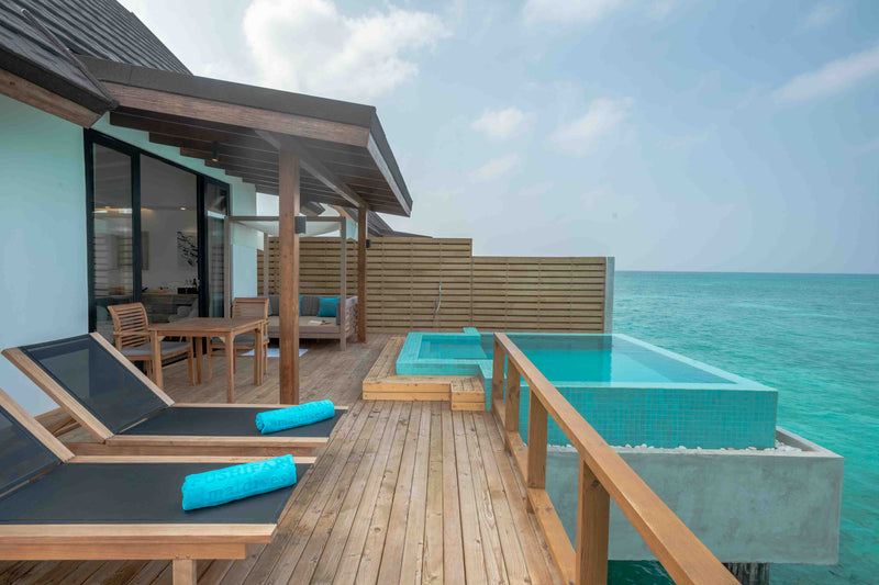 A thatched water villa and its deck over the lagoon at Fushifaru Maldives.
