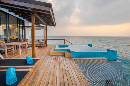 Fushifaru Maldives, Lhaviyani Atoll — sun loungers on a villa deck above the water at dusk