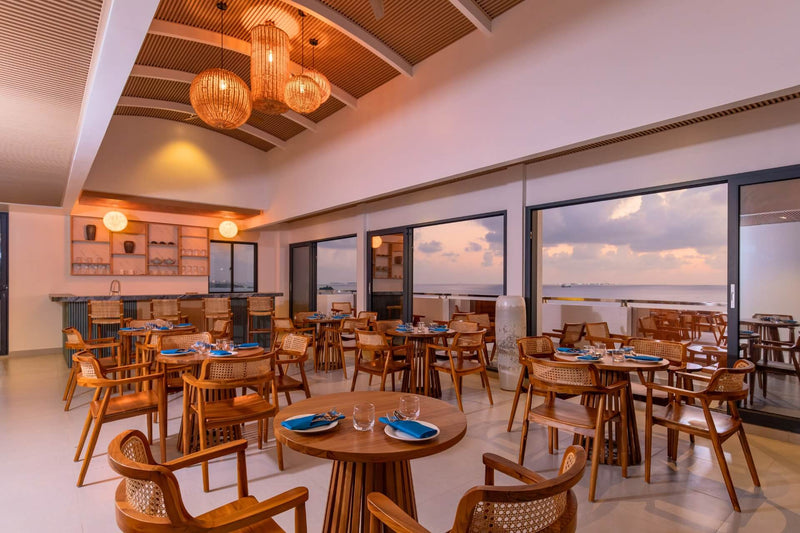 The Nest restaurant at Arrival Beach & Spa, with wooden tables by the windows