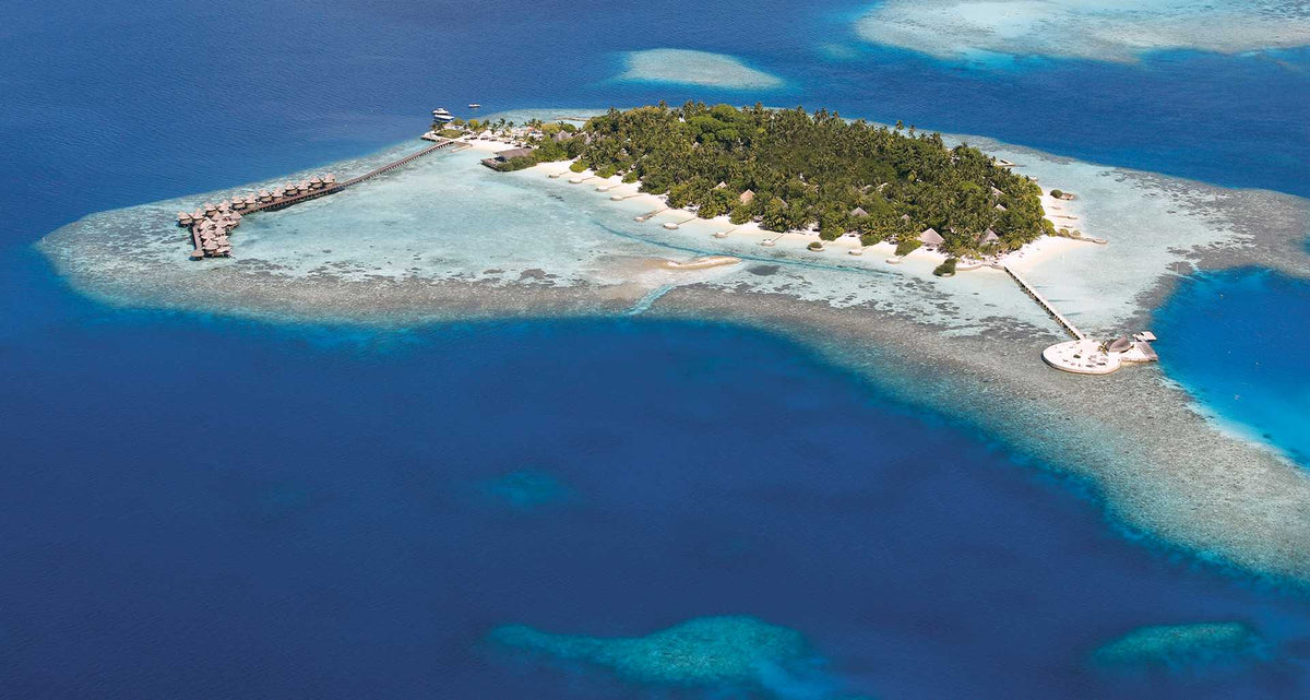 Nika Island Resort & Spa from the air, the wooded island tapering into a long pale sandbank