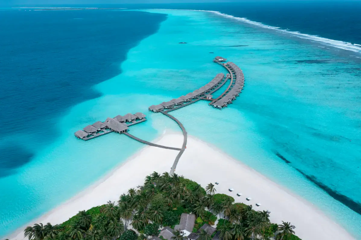 The overwater villa jetty at Niva Velassaru Maldives from the air, over the lagoon.