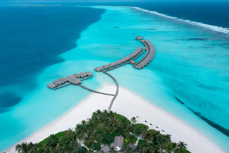 The overwater villa jetty at Niva Velassaru Maldives from the air, over the lagoon.