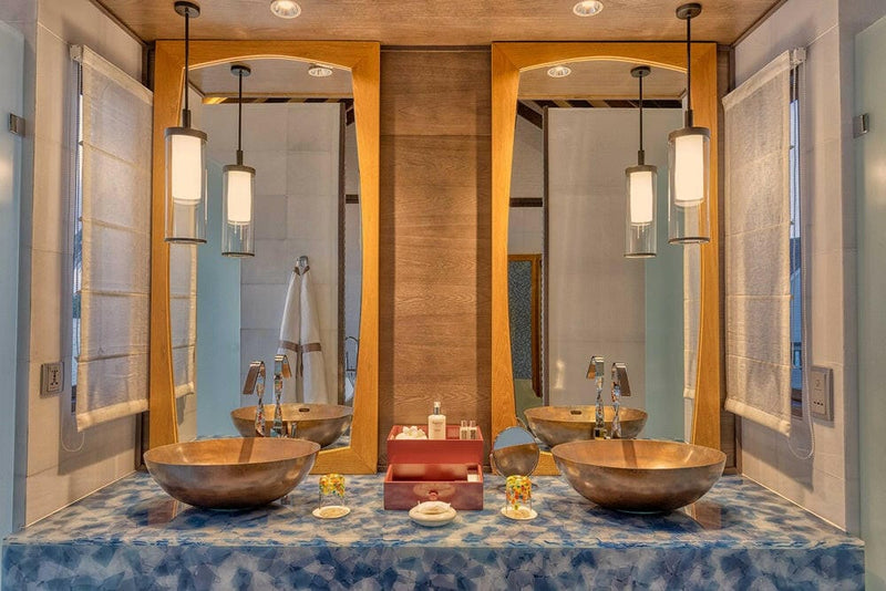 The bathroom of a Wind Villa at OZEN LIFE Maadhoo, twin hammered copper basins on a mottled blue counter