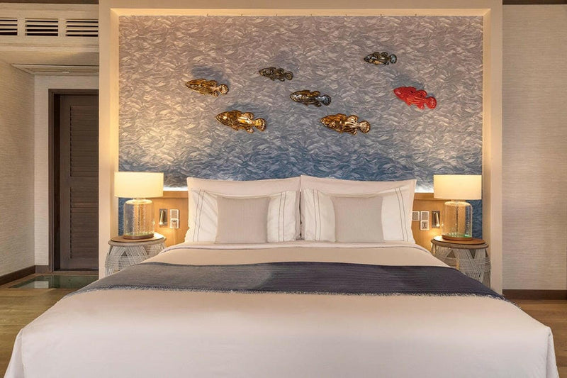 The bedroom of a Wind Villa at OZEN LIFE Maadhoo, ceramic fish mounted on the papered wall above the bed
