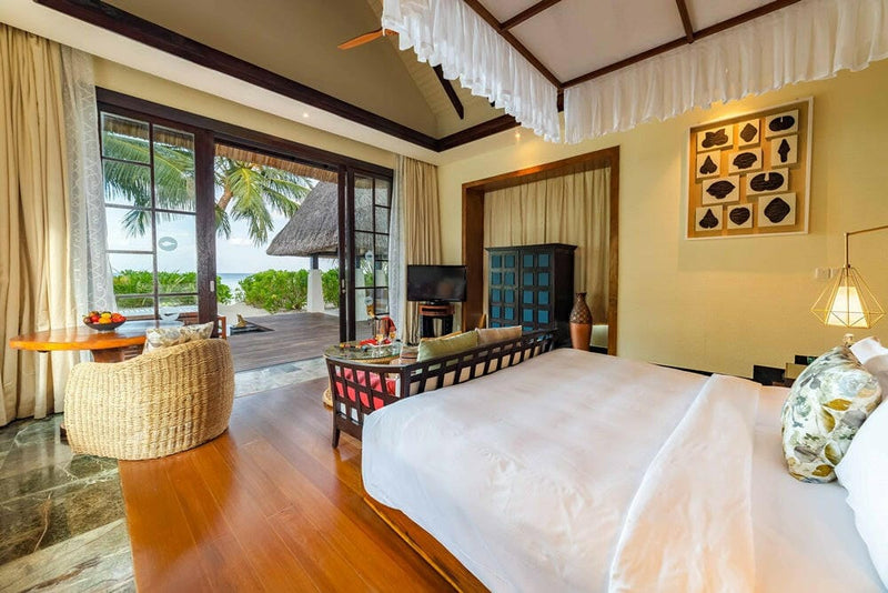 A villa bedroom at OZEN RESERVE Bolifushi, a white canopy over the bed and a framed shell display on the wall