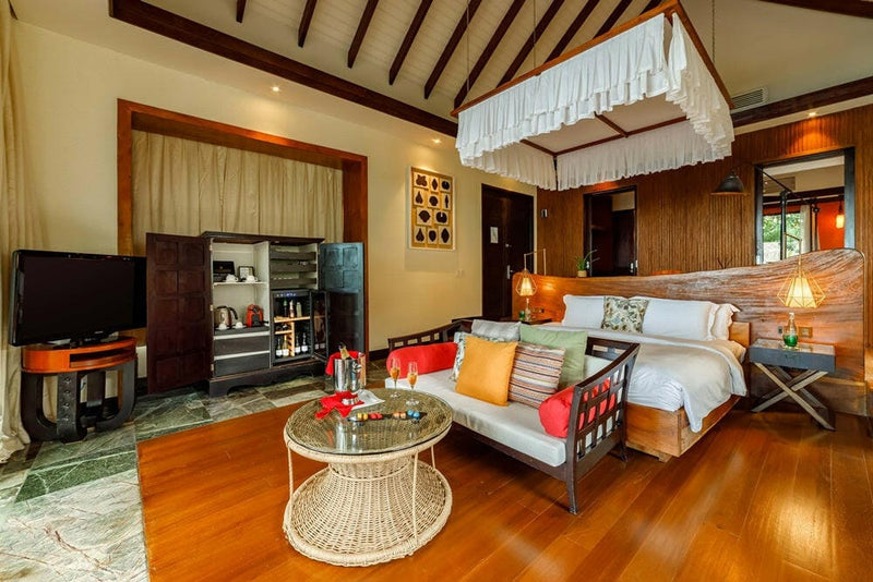 A villa bedroom at OZEN RESERVE Bolifushi, the drinks cabinet standing open beside the bed