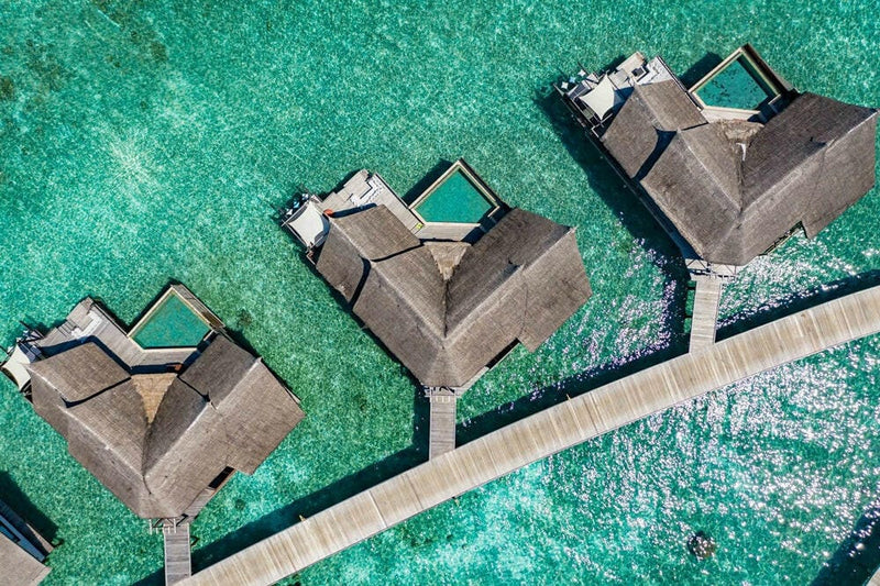 Water villas at OZEN RESERVE Bolifushi from above, thatched roofs and pools along the jetty