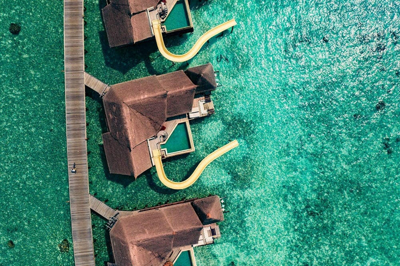 Water villas at OZEN RESERVE Bolifushi along the jetty, each with a slide dropping into the water