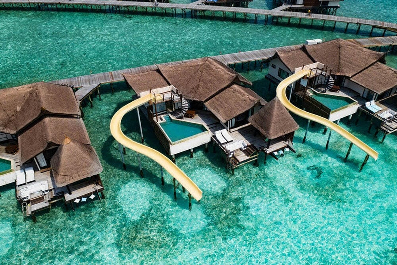 Water villas at OZEN RESERVE Bolifushi from the air, two pale slides curving down into the lagoon
