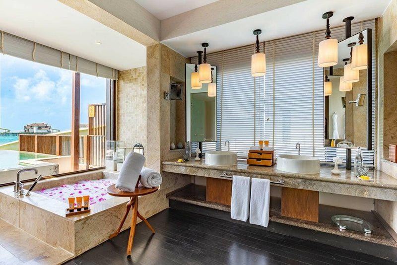A villa bathroom at OZEN RESERVE Bolifushi, a stone counter and mirror above a tub laid with a timber tray