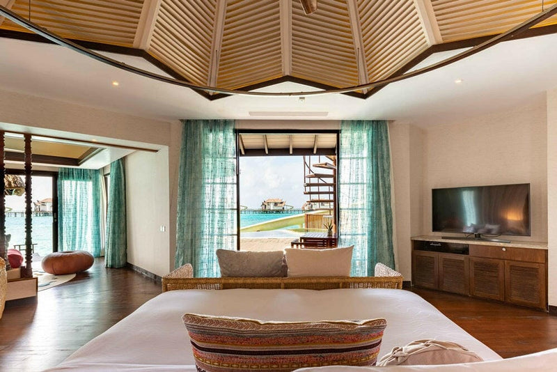 A villa sitting corner at OZEN RESERVE Bolifushi, a beige daybed and television under a slatted ceiling