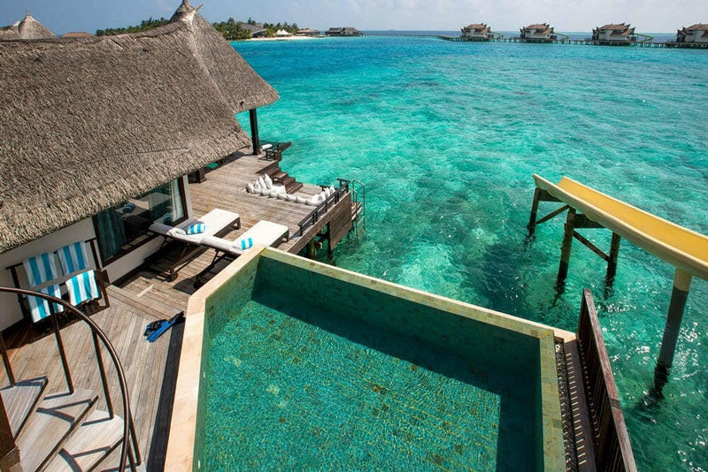 The pool deck of a water villa at OZEN RESERVE Bolifushi, the slide ramp beside it above the lagoon